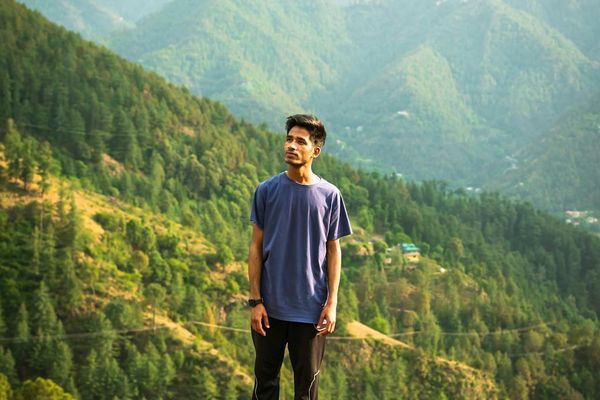 Young man standing on a hill enjoying fresh morning air